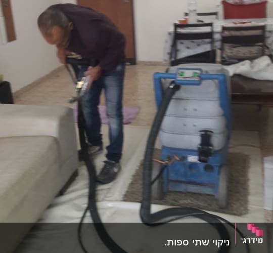 אדם מנקה ספה עם מכונת ניקוי מקצועית